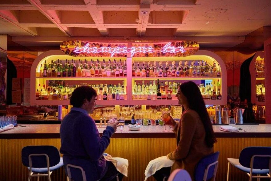 A pink cocktail bar with a neon sign 