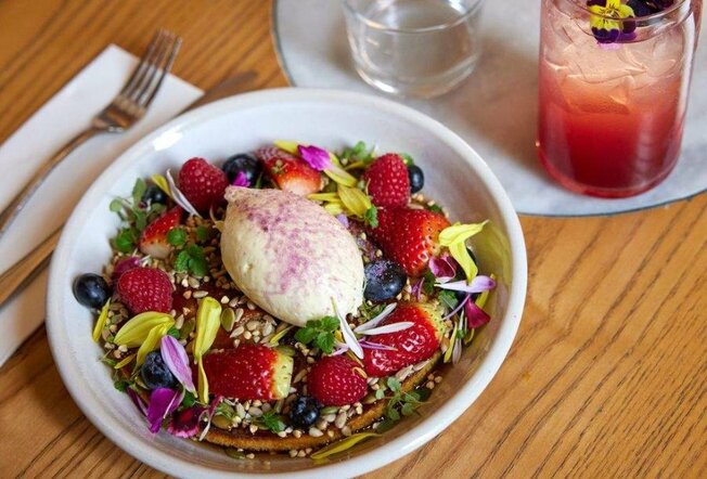 A pancake on a plate covered in fruit and flowers