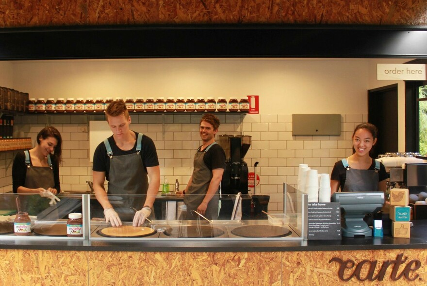 Four staff working behind the counter of a crepe cart.