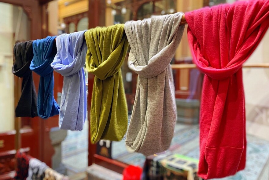 Several scarves hanging on a rack.