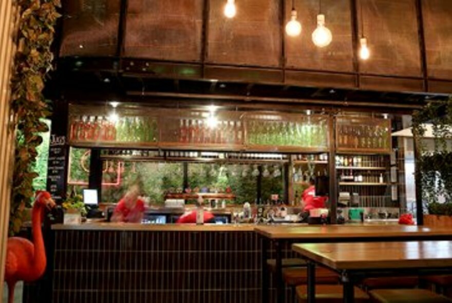 The interior of a bar with wood panelling and a large pink flamingo.