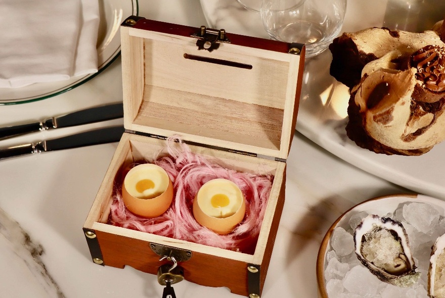 A restaurant table setting with oysters and a box containing two egg dishes.