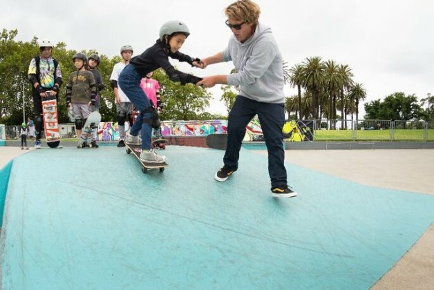 Person helping a small child to skateboard at Riverslide Skate Park.