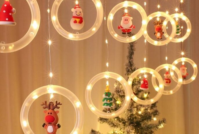 Assorted hanging Christmas lights, with a Christmas tree in the background.