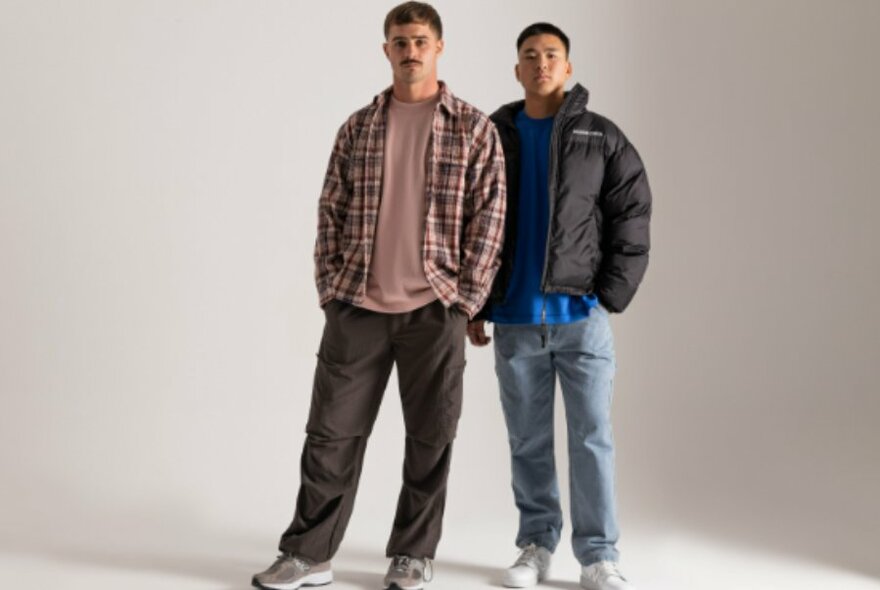 Two male models posing in fashionable casual streetwear against a white background.