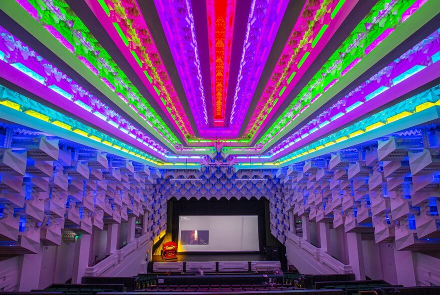 Inside a theatre lit up in rainbow colours