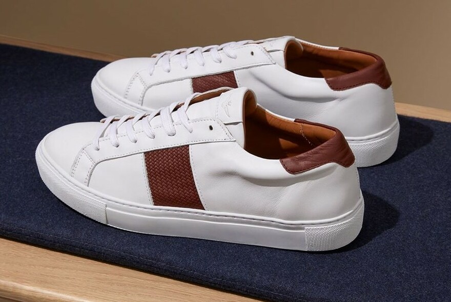 Pair of white and brown sneakers sitting on a pair of jeans.