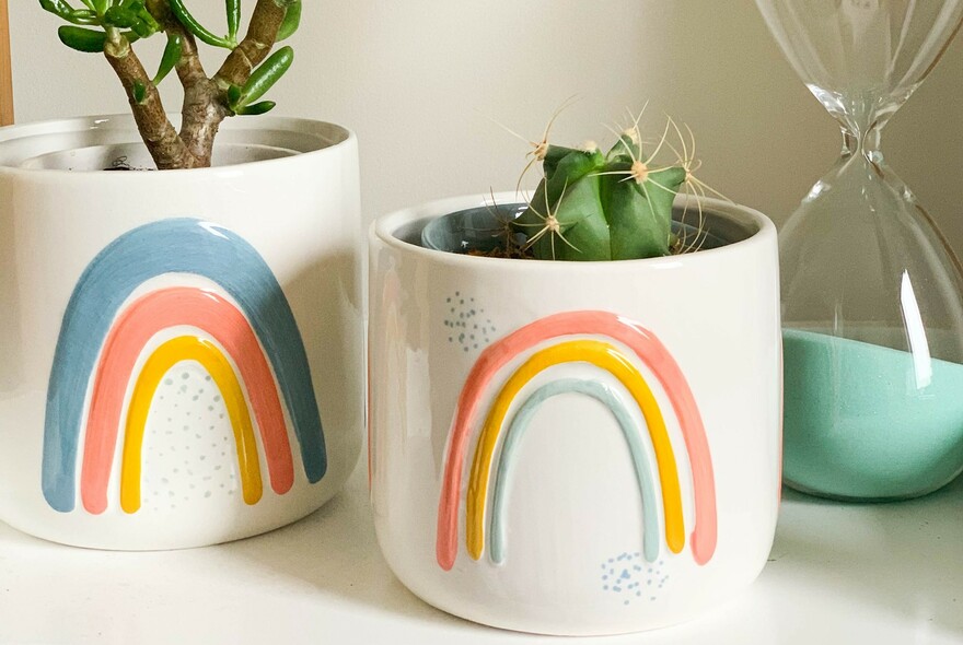 Two ceramic plant holders with rainbow motif.
