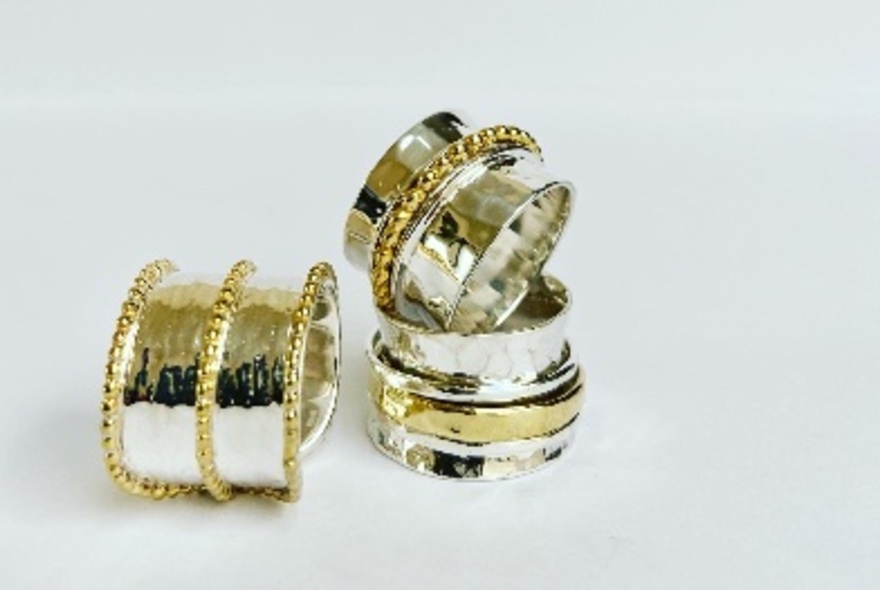 Three silver and gold rings displayed on a white background.