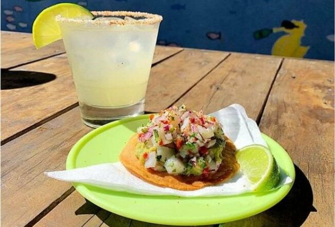 A margarita with salt and lime on a table with a taco.