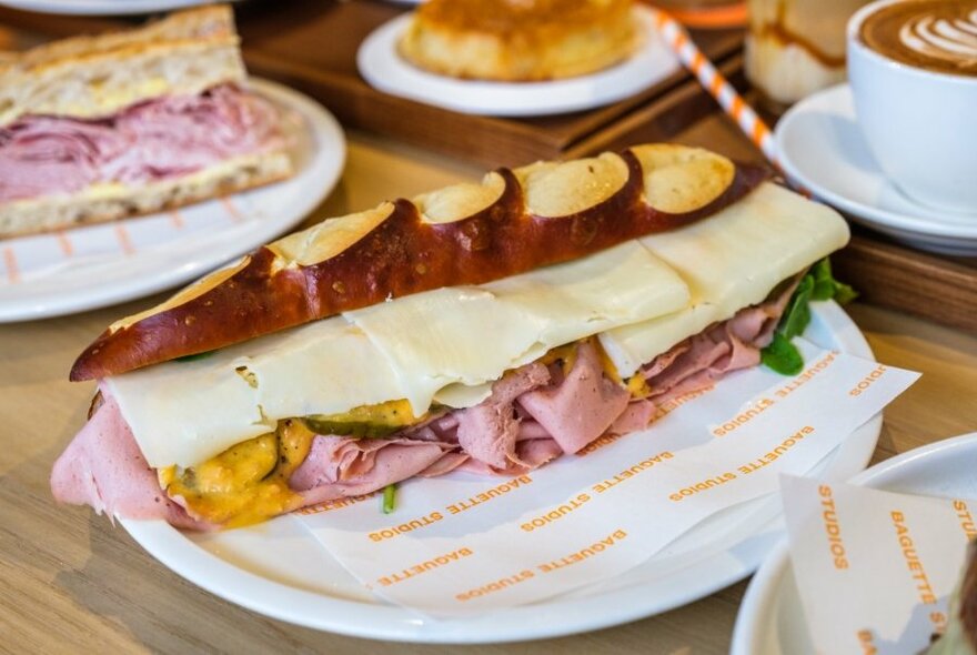 A large baguette sandwich made with pretzel bread and filled with meat and cheese.