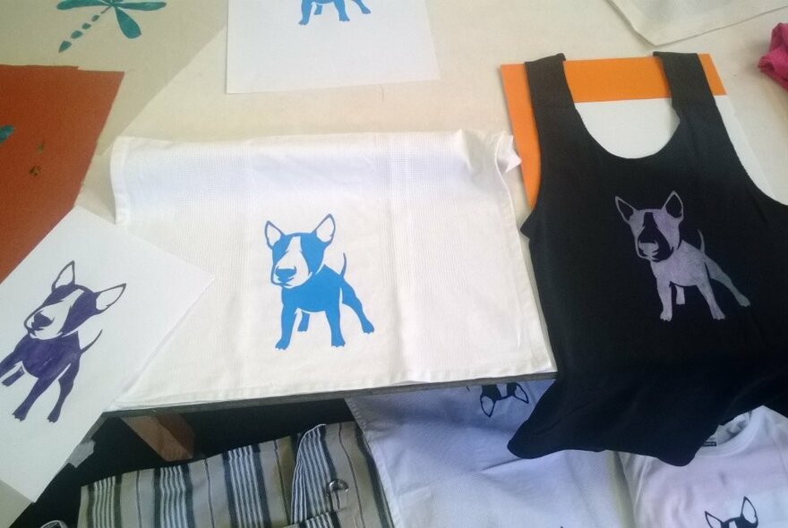 The results of screen printing with a dog design on a singlet and other pieces of fabric.