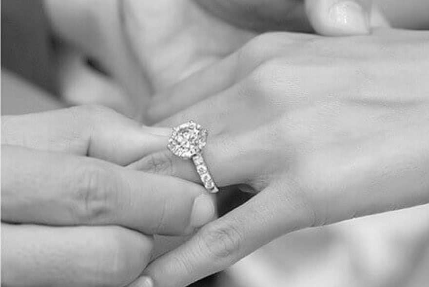 A diamond engagement ring on a finger.