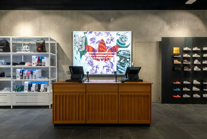 The counter at the Adidas store with a logo behind it and products on either side