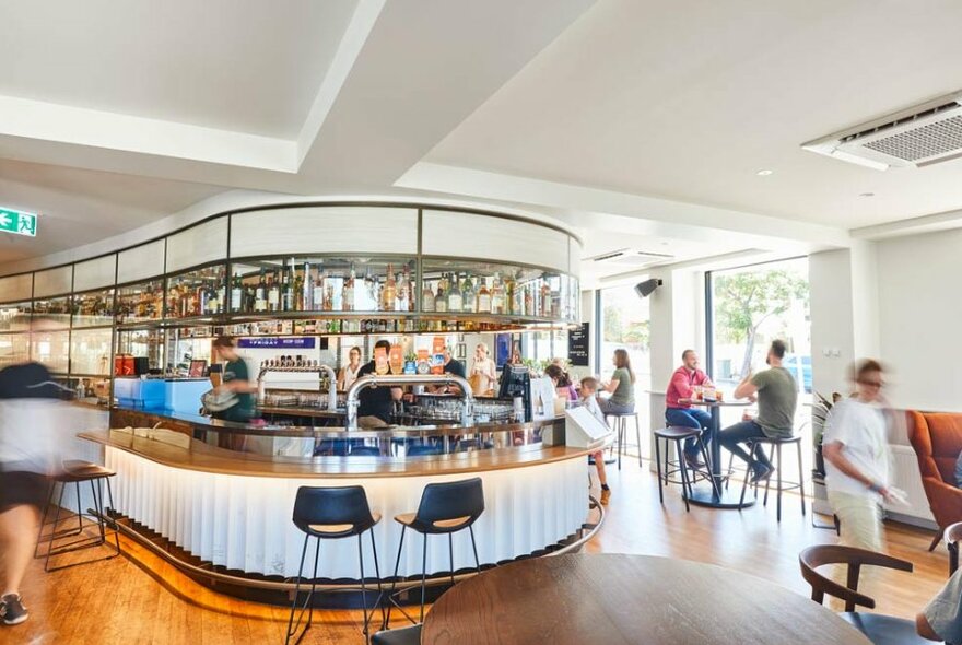 A busy pub with a curved bar and patrons at tables 