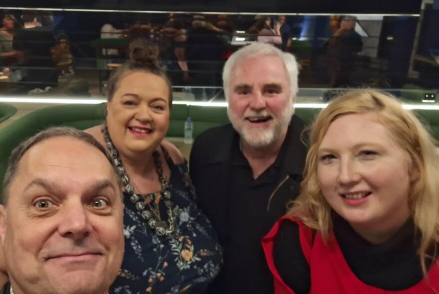 Four smiling people posed for selfie photograph.