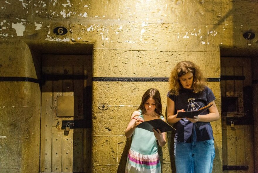 A mother and child in a jail cell at Old Melbourne Gaol, looking at pamphlets. 