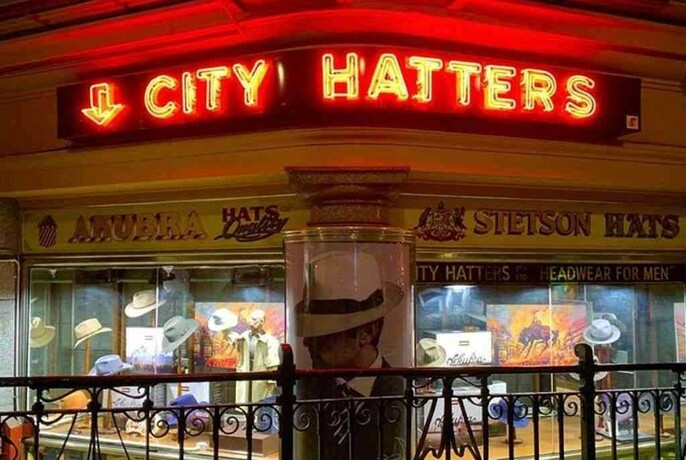 Neon City Hatters sign above the basement shop.