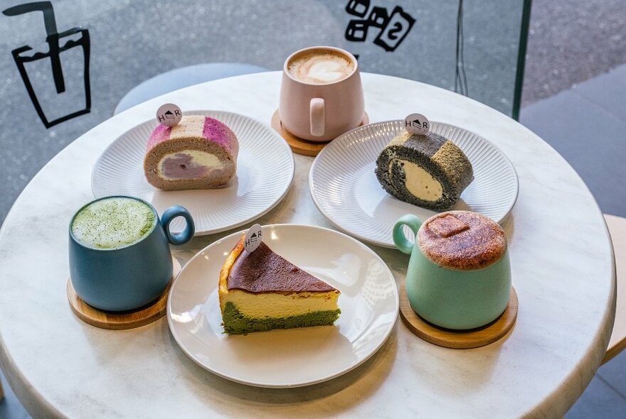 A cafe table set with colourful cakes and drinks.