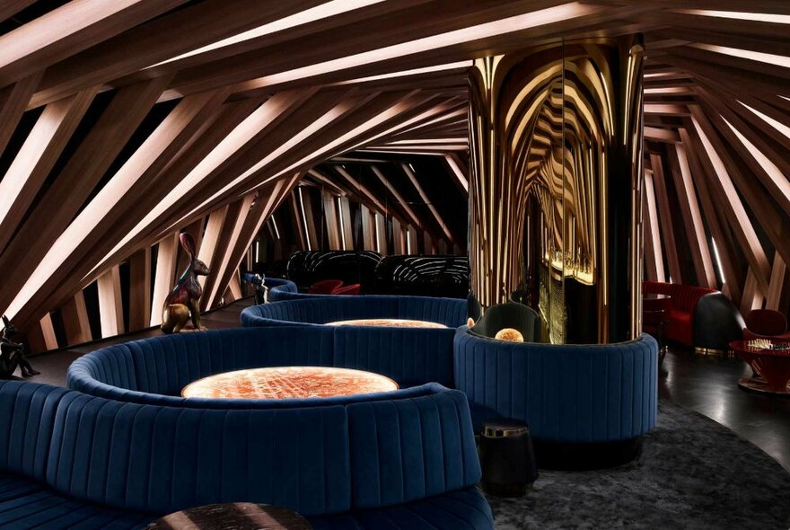 Interior of Curios Nightclub with blue velvet booth seating and a sloped, paneled architecturally designed ceiling