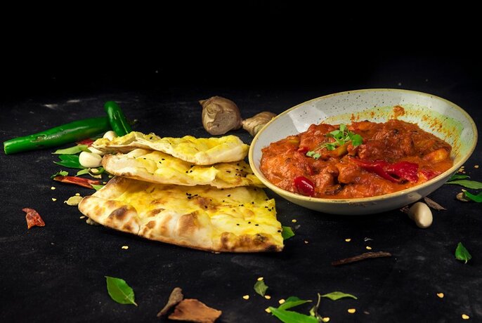 Indian bread, spices and curry on a black background.