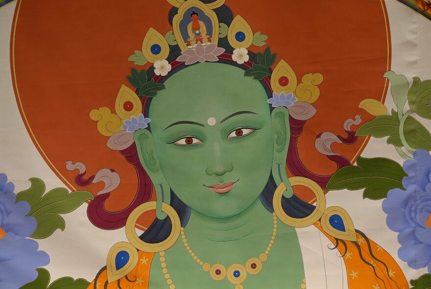 Green Tara image with flowers and looped gold jewellery.