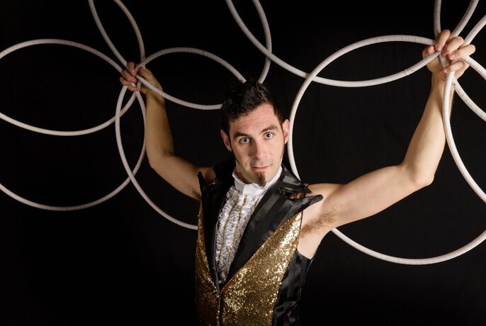 A man holding intertwined large rings looking intently ahead.