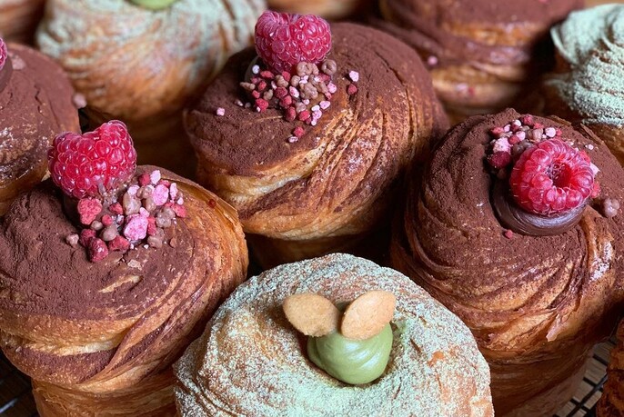 Pastries dusted with chocolate and decorated with sprinkles and raspberries.