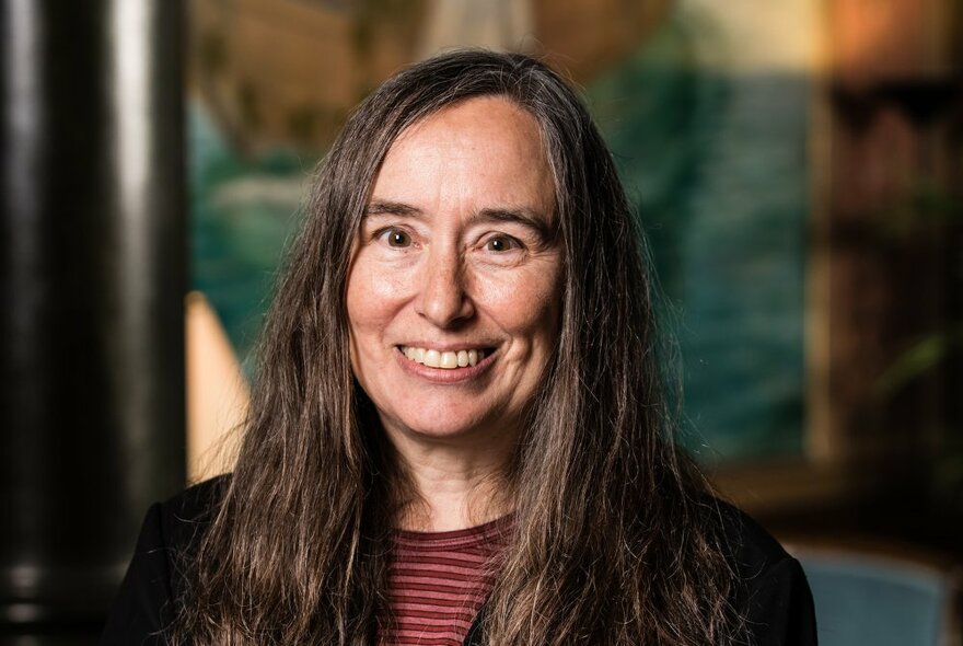 Professor Susan Coppersmith with long hair and a striped shirt, smiling.
