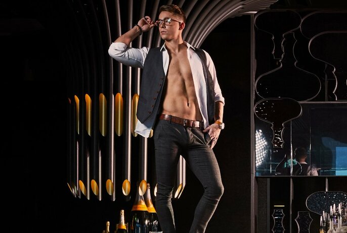 Performer, with open shirt and glasses looking to the right.