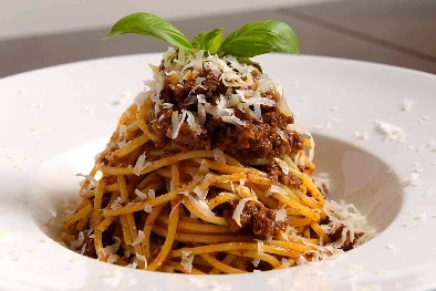 Spaghetti and meat arranged on the plate in a conical mound shape.