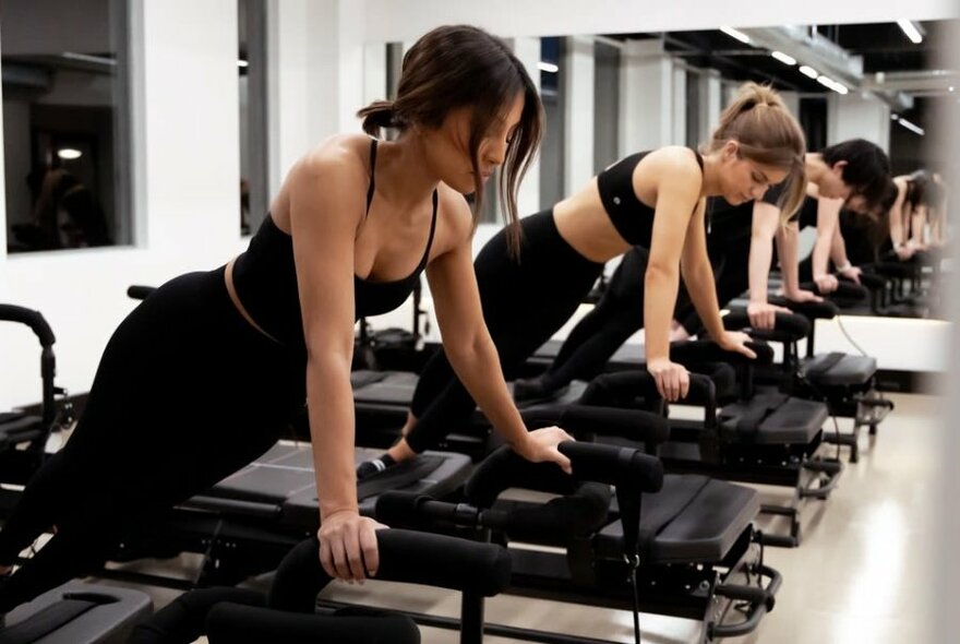 People exercising on a Megaformer machine in a studio space.