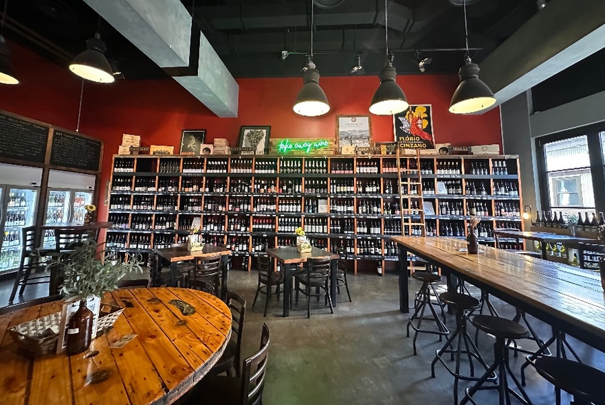 Wine bar interior with shelves of bottles and wooden tables.