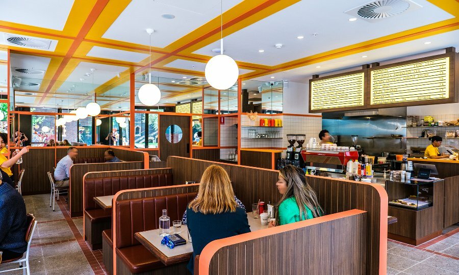 People dining in timber booths at a retro style diner. 