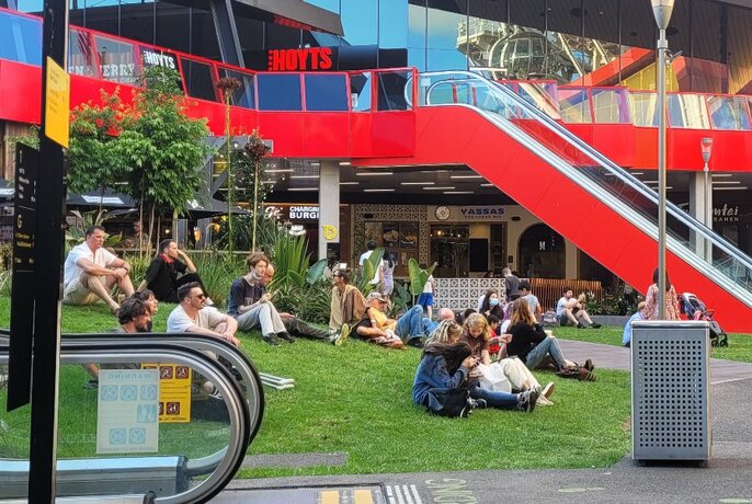 People at The District Docklands sitting on the grass.