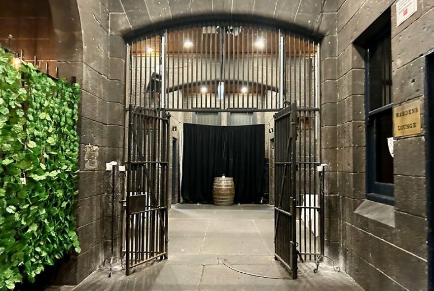 A stone building with a iron gate wide open to reveal a keg. 