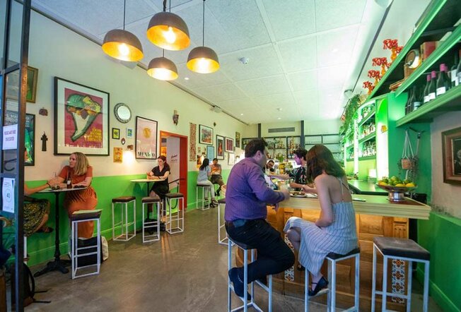 People sitting at the bar in a bright green restaurant.