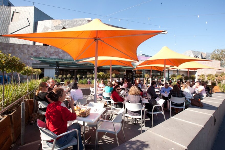 Patrons sitting outside under shade umbrellas at Time Out cafe in Fed Square.