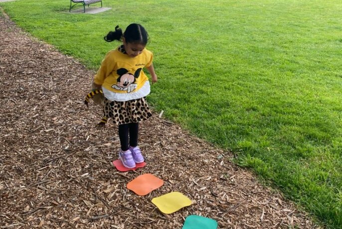 A child playing hopscotch in a park.