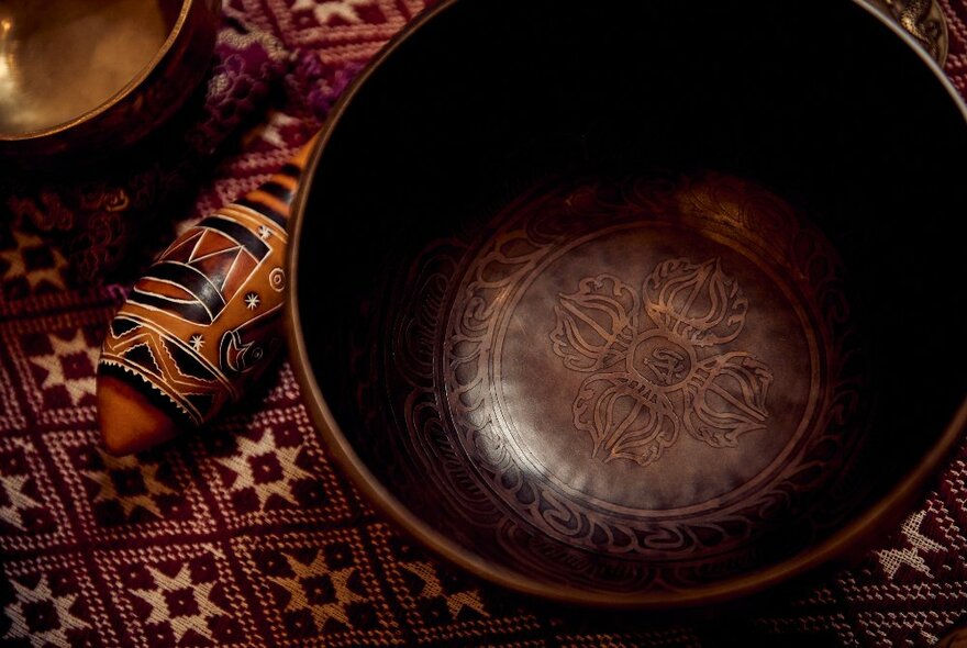 A dark toned image of a brown bowls on a patterned cloth. 