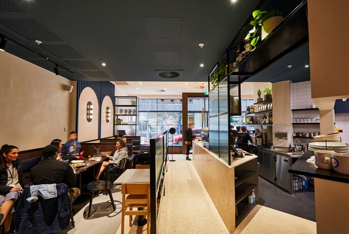 Interior of Maverick café showing seated diners and the open plan kitchen.