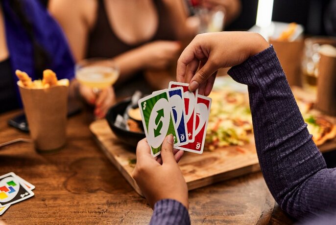 People playing a card game while eating snacks. 
