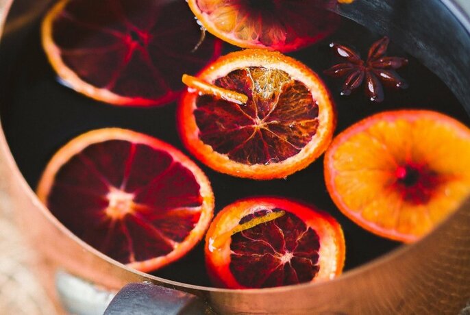 Pot of simmering mulled wine with slices of orange floating on the surface.