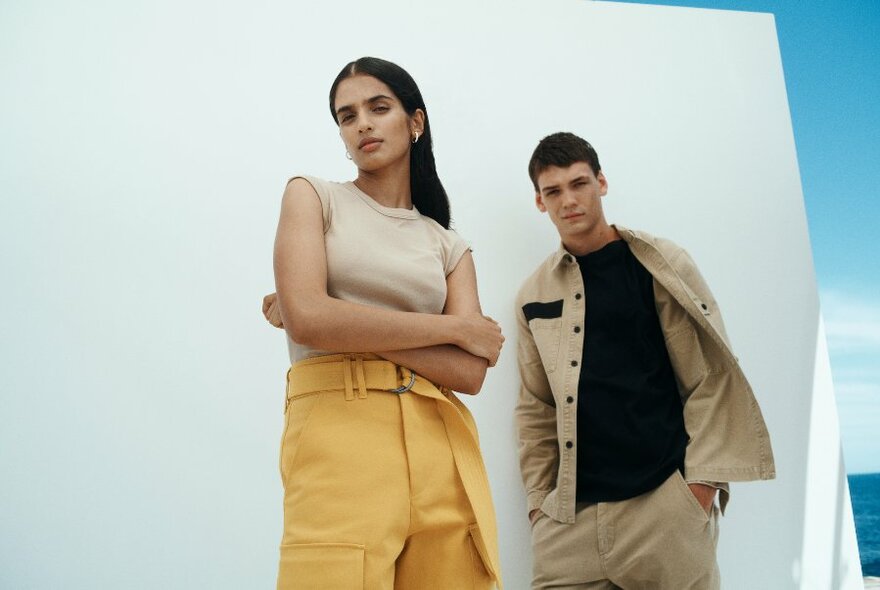 Two models wearing neutral coloured clothing standing against a white backdrop.