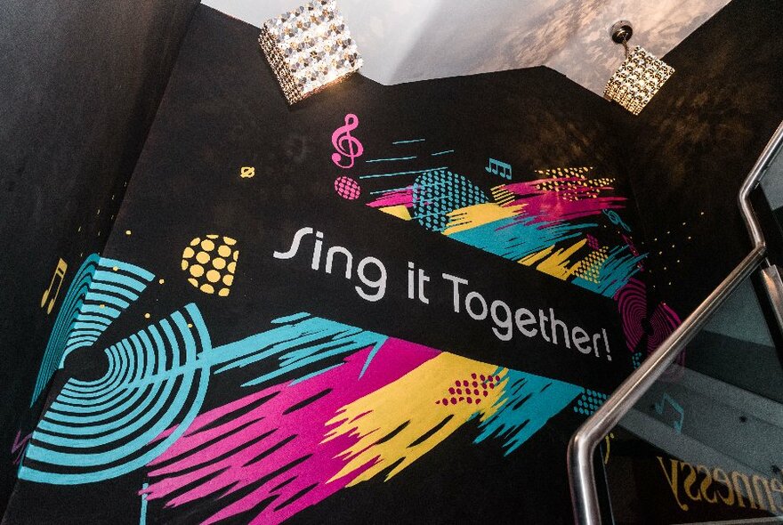 Painted wall with splashes of bright colours that says sing it together