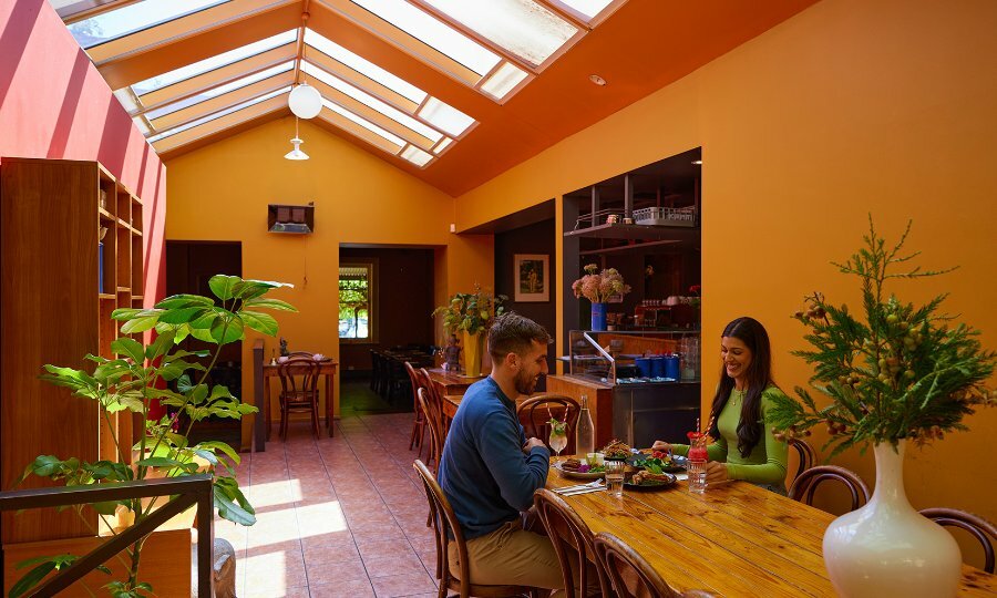 A couple dining at an orange restaurant with skylights letting sun in. 