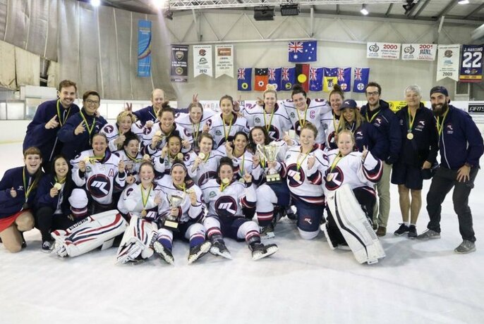 Melbourne Ice Hockey team gathered on the ice holding medals with support team.