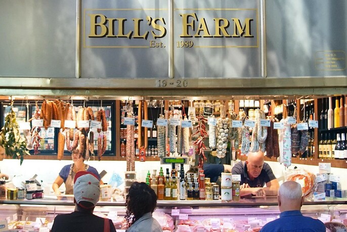 Exterior of Bill's Farm with man serving customers. 
