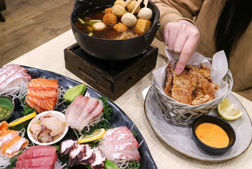 Hand selecting food from a selection of dishes including large seafood platter.