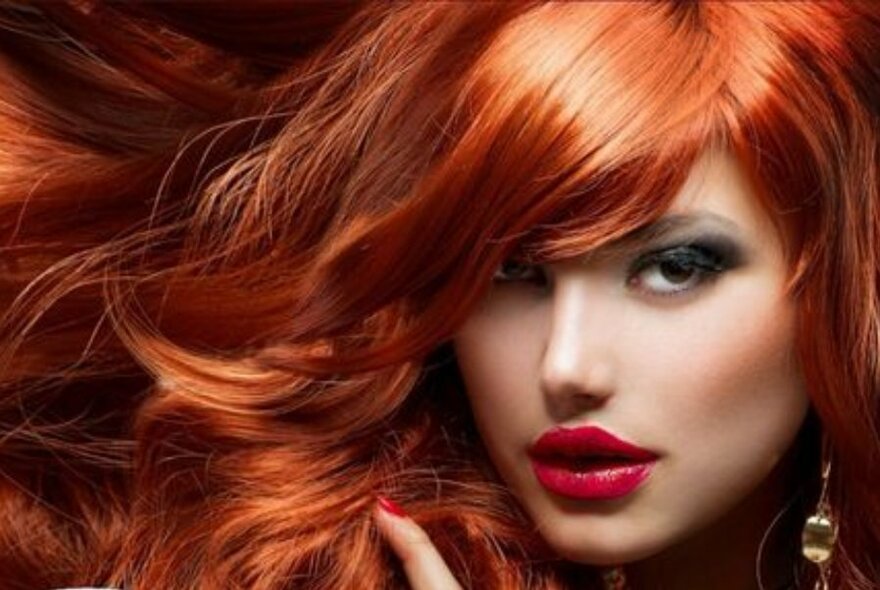 Model wearing a long red wig and heavy make-up.